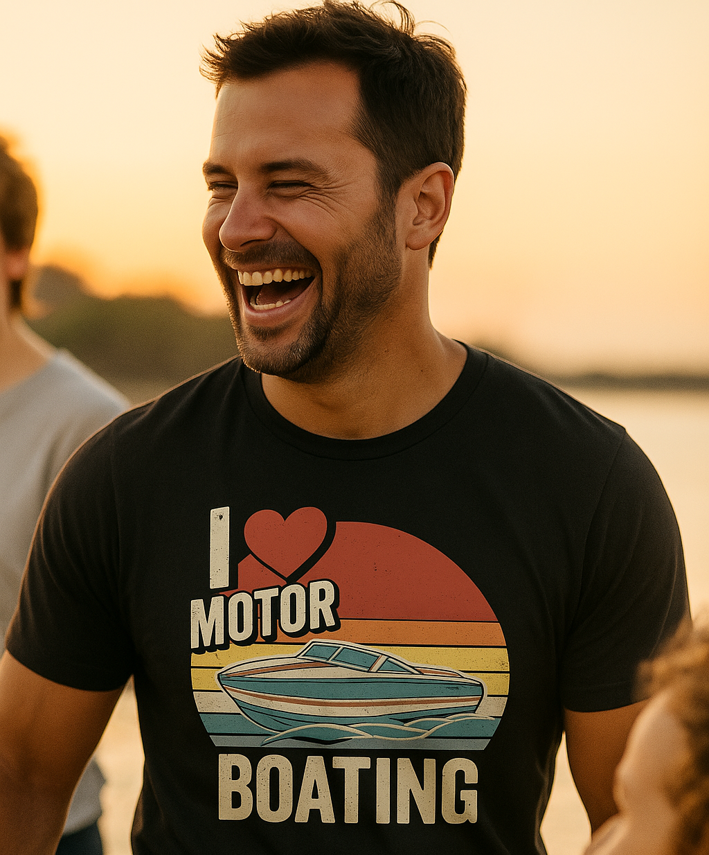 Man wearing a 'I ❤️ Motor Boating' t-shirt by a body of water at sunset.
