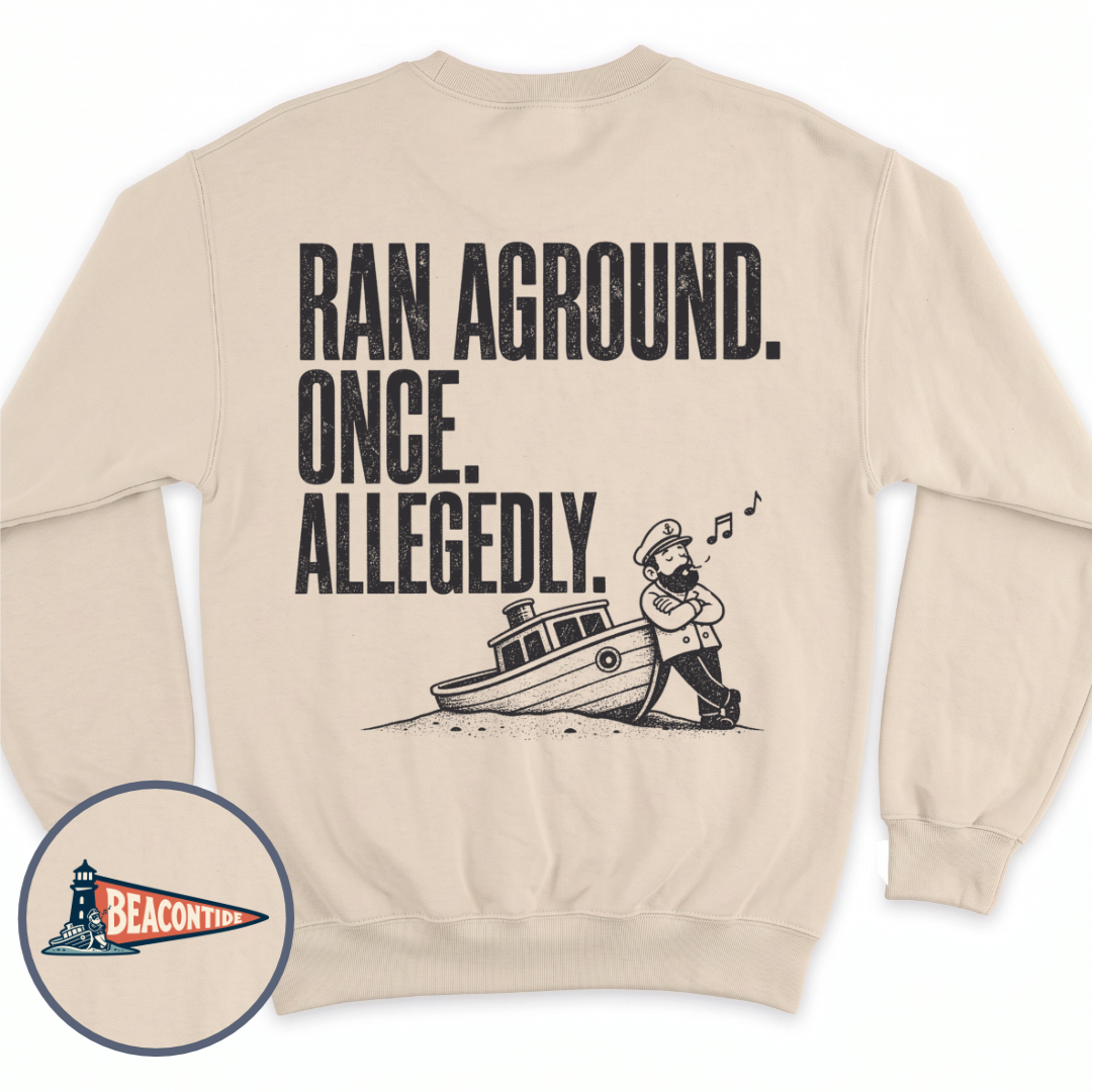 Allegedly Ran Aground crewneck sweatshirt in Sand, back view — Ran Aground. Once. Allegedly. with a captain leaning on a grounded boat, BeaconTide
