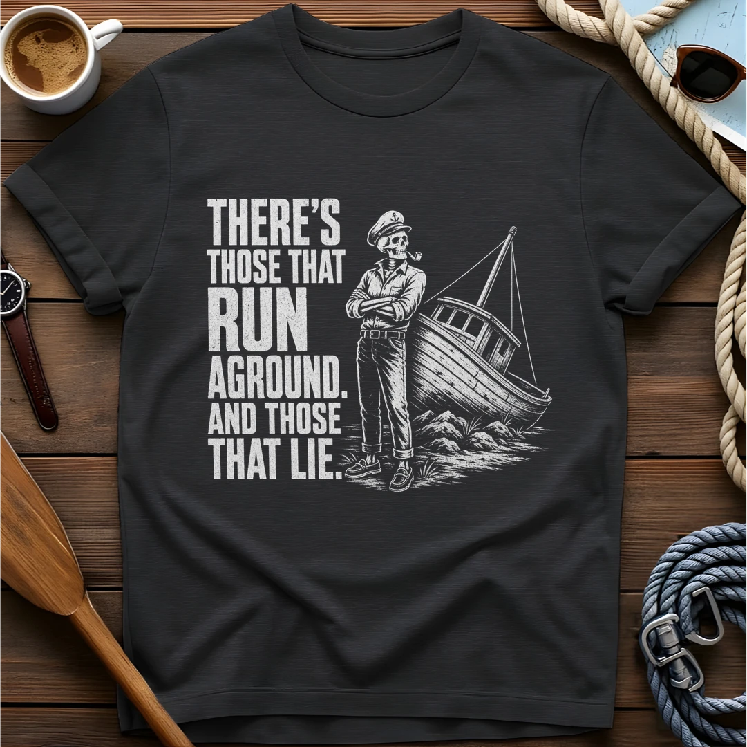 T-shirt with a skeleton captain smoking a pipe beside a sailboat run aground on rocks and text reading 'There's those that run aground. And those that lie.'